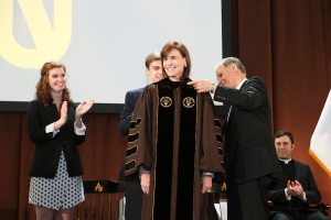 Riordan accepts the symbols of the office, the President’s Medallion and a University hood in the school’s colors of brown and gold.