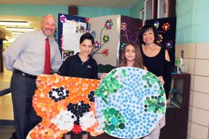 From left: Village Elementary School Principal Jeffrey Kasper, student council officer Andrew Fazzolari, Earth Keepers Club officer Alyssa Pinto and student council adviser Eileen Hoffman display some of the fine bottle cap artwork. 