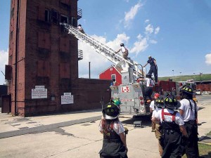 The firefighters prepare to climb a ladder.