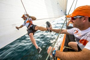 January 4, 2015. Leg 3 onboard Team Alvimedica. Day 1. Sunrise in the Straits of Hormuz after a busy night of sailing north along the UAE coastline. Dave Swete gets a hand from Seb Marsset while he repairs a rip in the A3 sail.