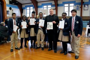 Members of the St. Mary’s High School Literary Club—“Phoenix” proudly share their work with Fr. Robert Romeo, pastor of the Church of Saint Mary.