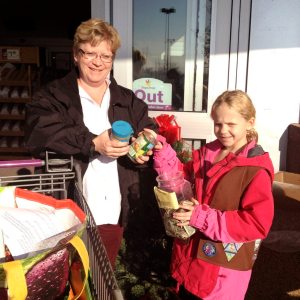 Port Resident handing canned  food donations to a Brownie  Troop #443 member