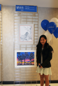 Great Neck South Middle School student Cheryl Chan stands with her artwork during opening night of the showcase.