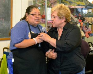 Senior center member Mickey and center cook Maggie sing Feliz Compleanos to the summer birthday babies 