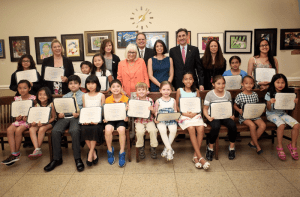 Councilwoman Lee Seeman, Town Supervisor Judi Bosworth, Receiver of Taxes Charles Berman, Councilwoman Dina De Giorgio, Town Clerk Wayne Wink and GCAC Associate Director Caroline Sorokoff are with student artists from the Gold Coast Arts Center.