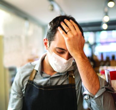 Worried owner with face mask at his small business