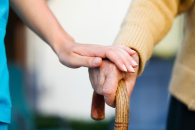 Care provider holding senior patient’s hand