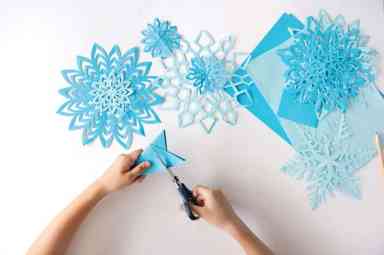 The child does snowflakes of blue paper.