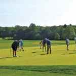 golfers warming up on the practice putting green