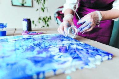 Artist mixing acryl paints on the picture working in fluid art technique