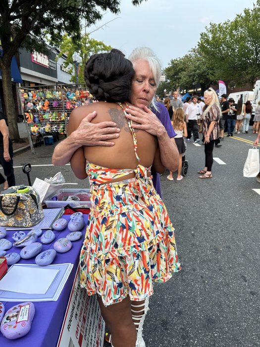 Carole Trottere hugging a woman who made a rock dedicated to a lost loved one