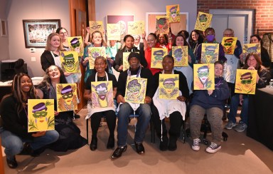 Attendees holding up their finished Mardi Gras painting at Westbury Arts Paint & Sip Night.